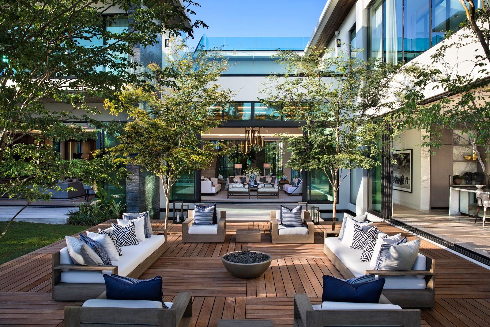 Central courtyard with a wood deck, outdoor lounge seating around a fire bowl and glass walls into the living spaces
