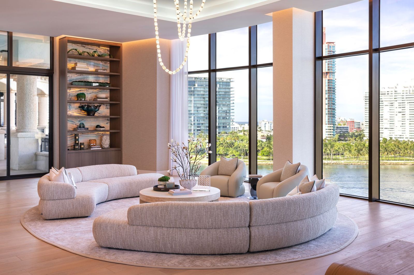 Bart Reines residence living room with curved sectionals and floor-to-ceiling windows overlooking the water and skyline