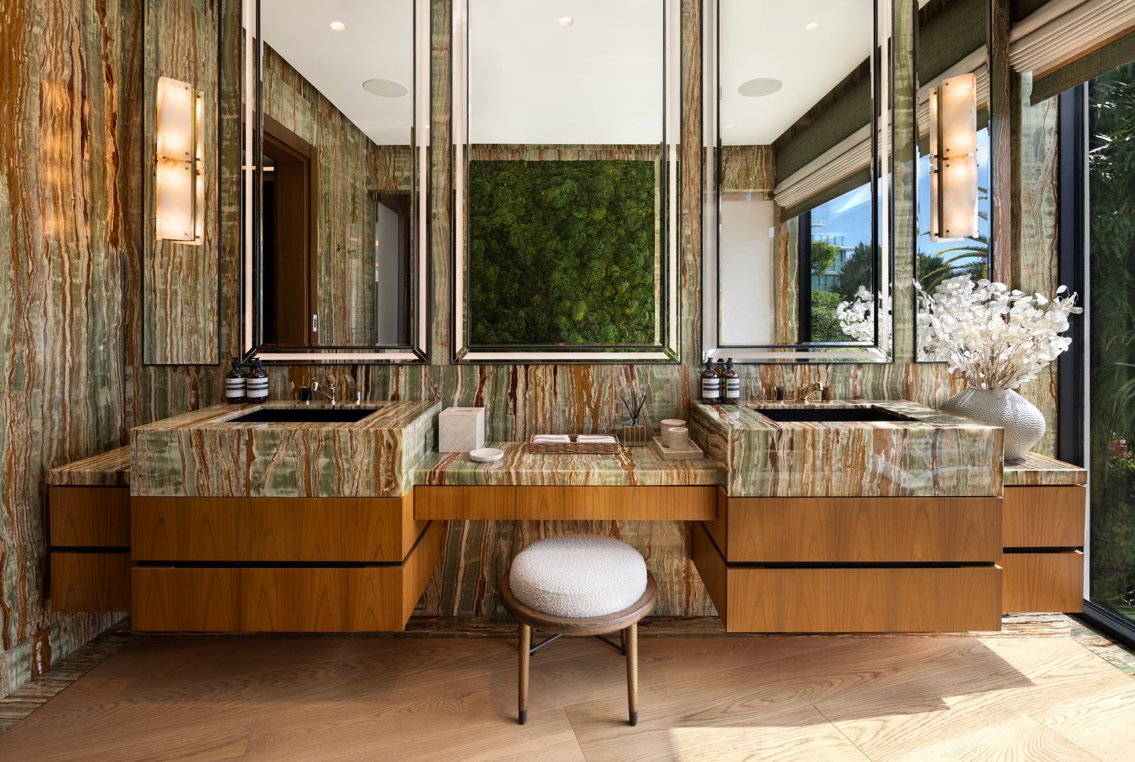 Bathroom with green onyx walls, dual onyx vanities on wood cabinetry and a living moss panel between the mirrors